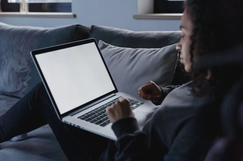 A woman comparing options on a laptop in her living room.