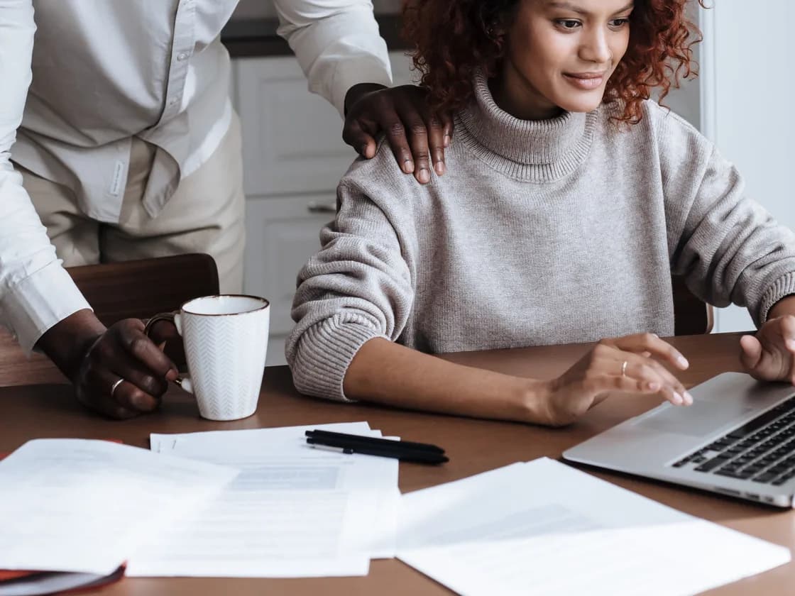 One person looking over another's shoulder at a laptop screen.