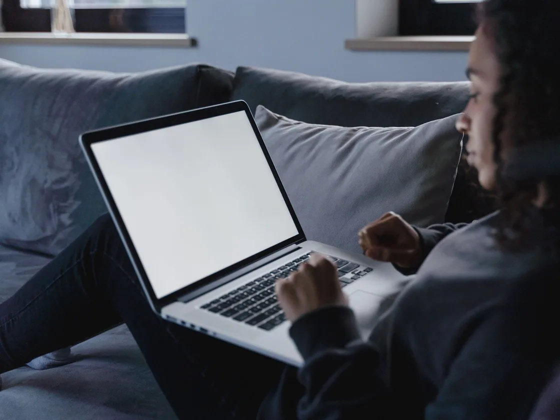 A woman comparing options on a laptop in her living room.